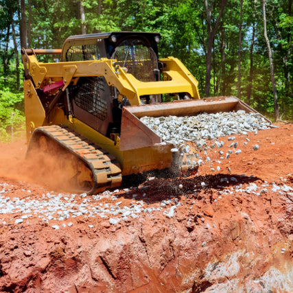 Earthmoving RentalsA yellow bulldozer on a dirt site dumps gravel from its bucket, kicking up dust. Dense green forest in the background contrasts with the red earth.